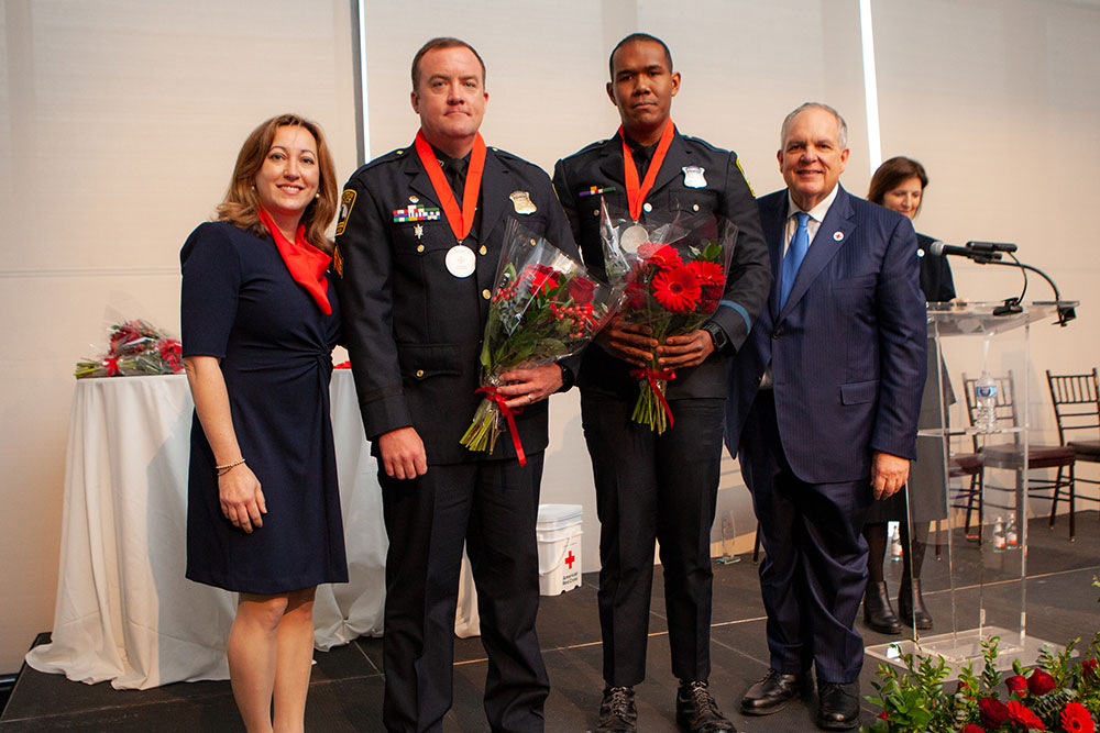 Group photo of Law Enforcement Heroes wearing medals and holding  bouquet of flowers