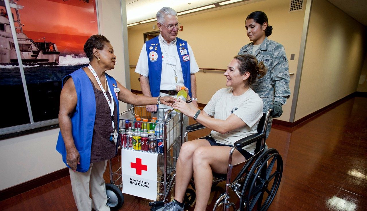 volunteers and US service member assisting woman in wheelchair