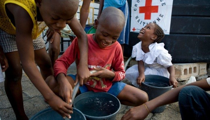 group of happy children pouring water hose in bucket