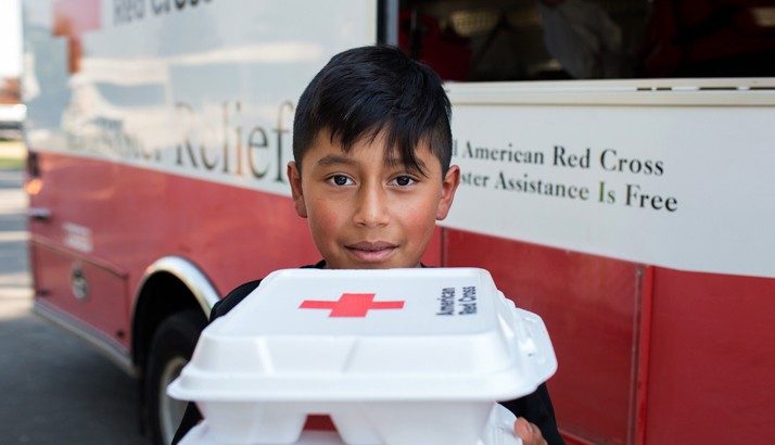 young boy holding food from disaster relief vehicle