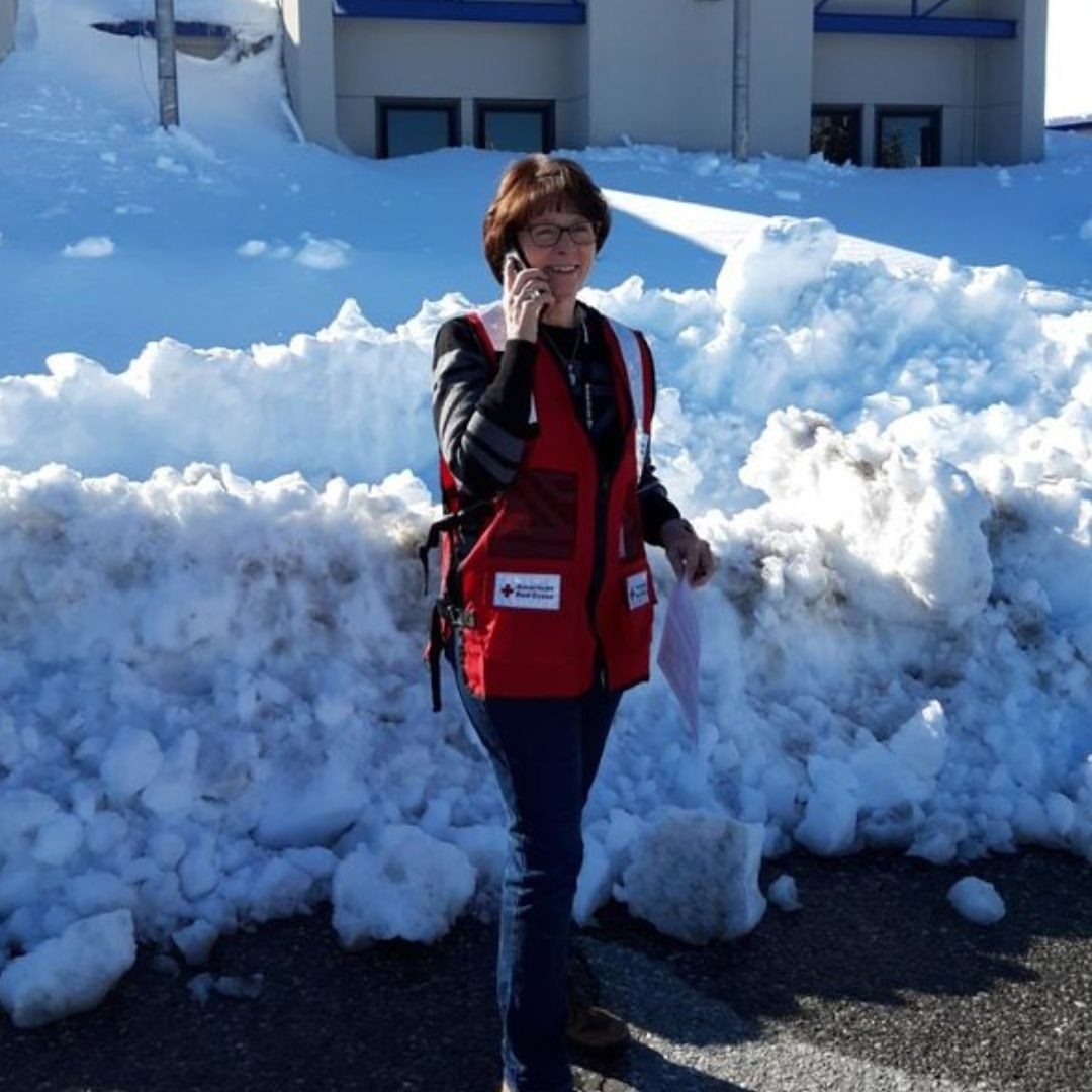 volunteer in front of red cross shelter blocked off by snow