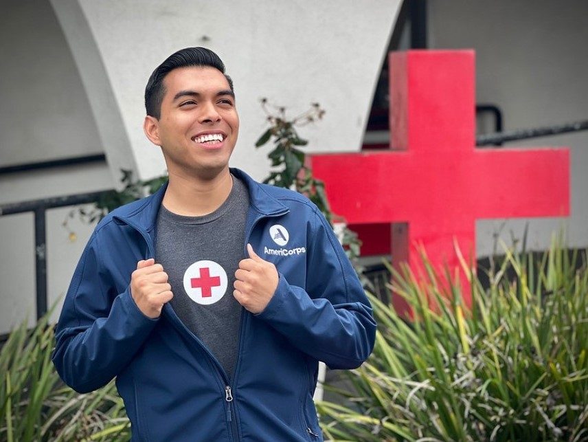 A person smiling with a red cross on his shirt