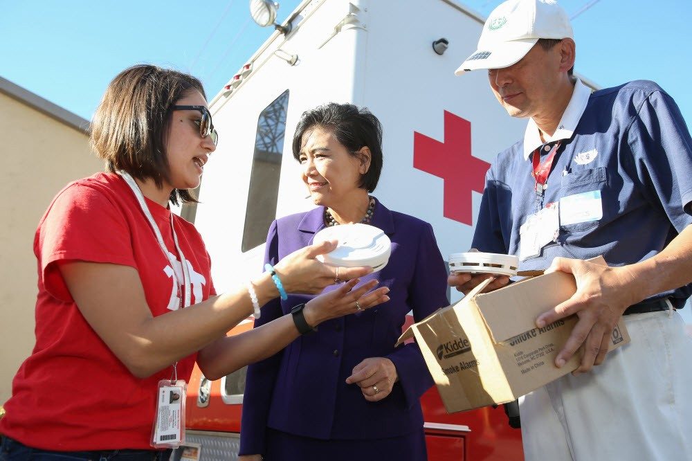 Red Cross volunteers showing smoke alarms to woman