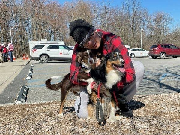 A man hugging two dogs