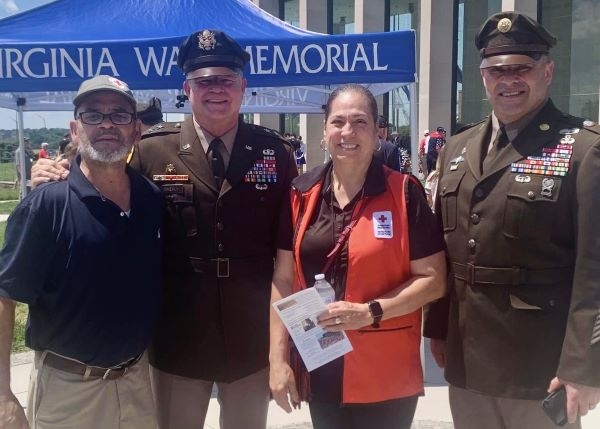 two military memeber in uniform standing  with red cross volunteer and family