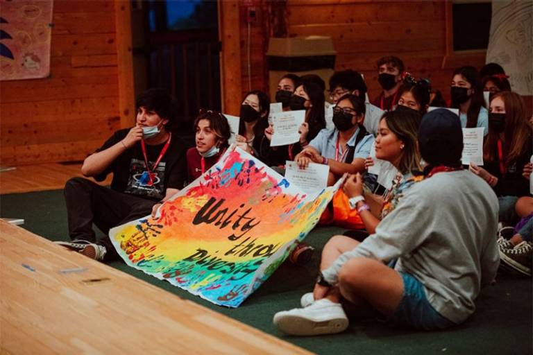 Group of youth sitting on floor holding signs