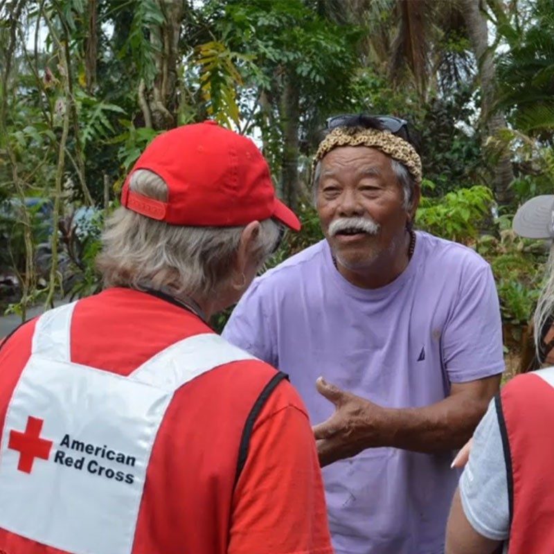 Red Cross volunteers speaking with man.