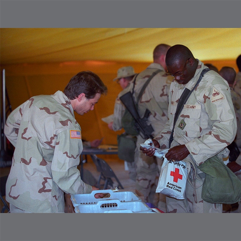 Military members one holding Red Cross gift bag