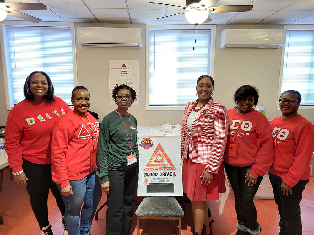 Members of the Bronx Alumnae Chapter of Delta Sigma Theta Sorority, Inc. stand alongside the Red Cross Blood Donor Ambassador volunteer.