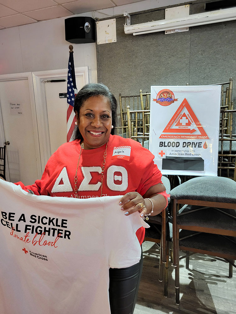 Dr. Angela Green holding t-shirt after donating blood at their blood drive with the Red Cross.