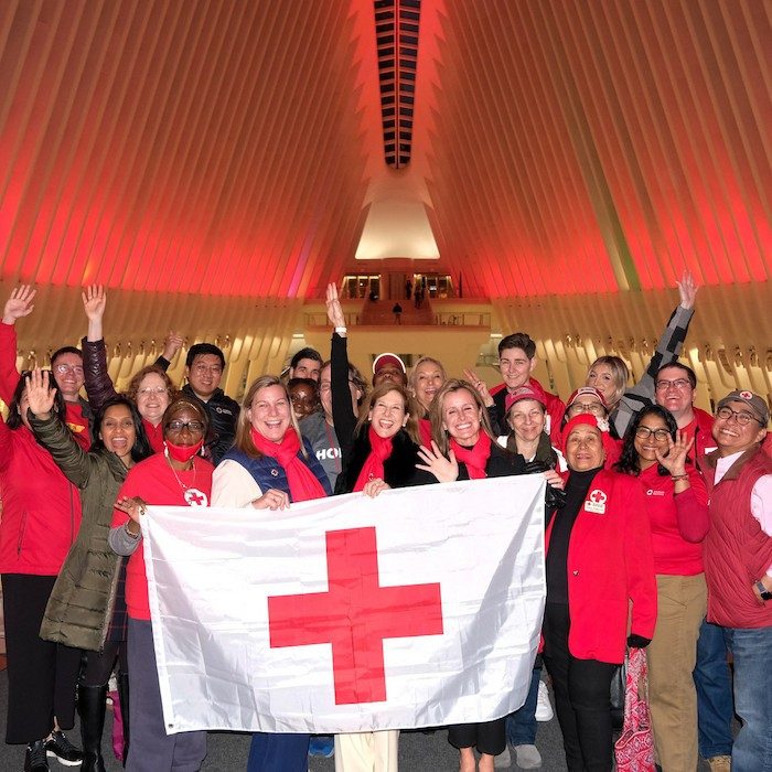 Landmark lit up in red with Red Crossers holding a Red Cross flag