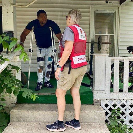 Red Cross volunteer helping man with crutches