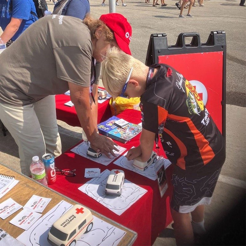 Red Cross volunteer teaching kid CPR at Iowa Speedway.