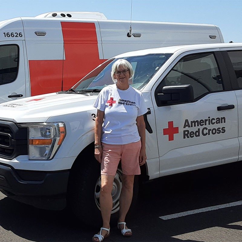 Red Cross volunteer standing next to Red Cross vehicles