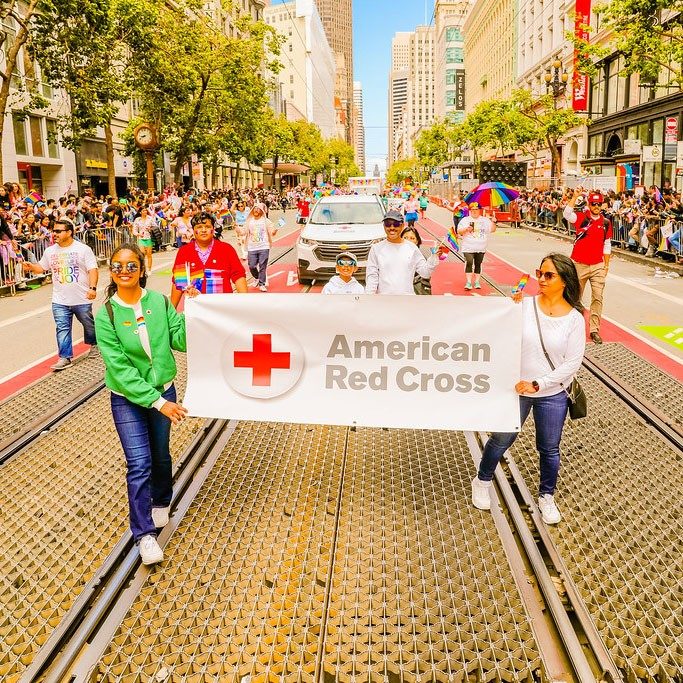Red Cross banner being held in PRIDE Parade.