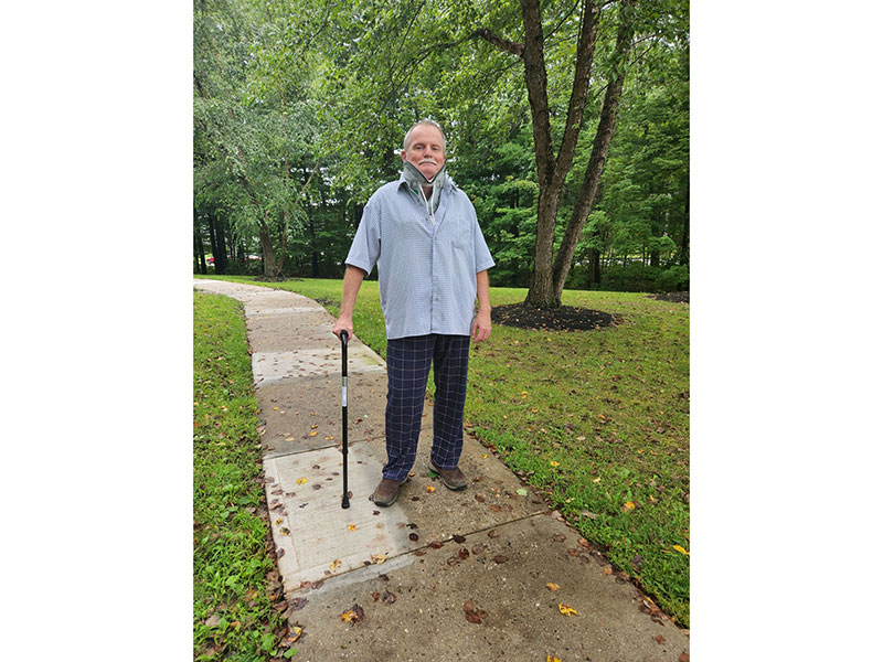 Mark Munson standing with cane in a park