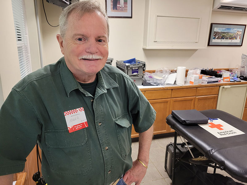 Mark Munson smiling in room with Red Cross cot
