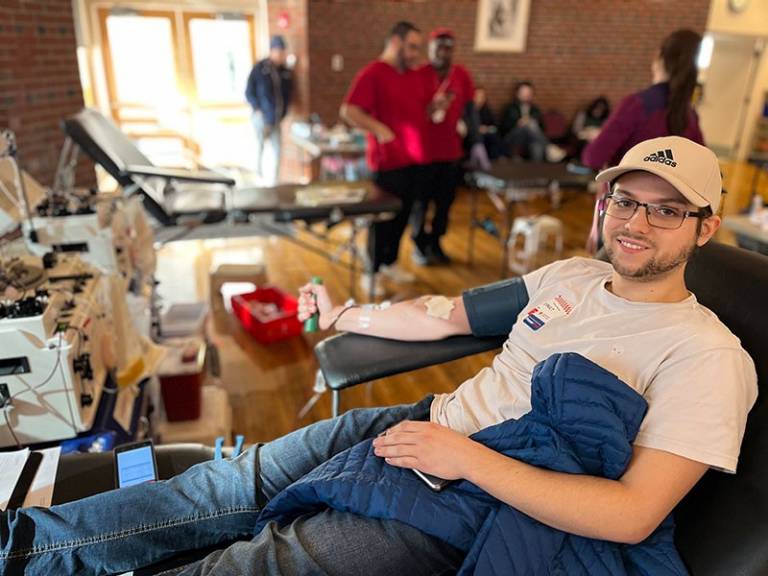Man sitting on cot donating blood.