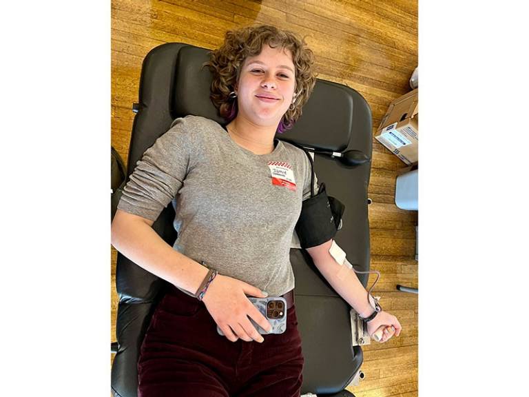 Woman laying on cot donating blood.