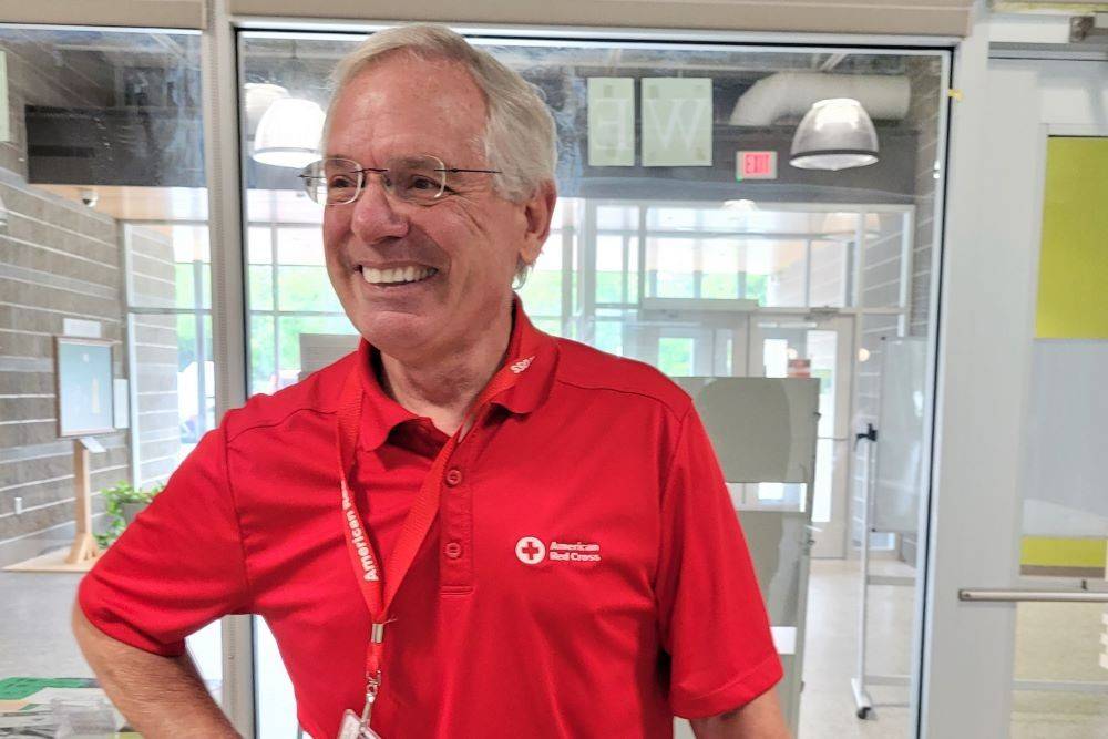 Kirk summers smiling in a red cross shirt