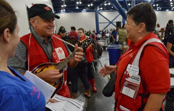 Red Cross volunteer playing a string instrument in wherehouse full of volunteers