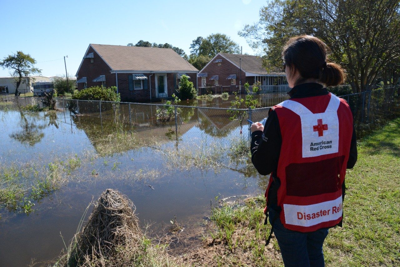 Red Cross volunteer looking at flooded houses
