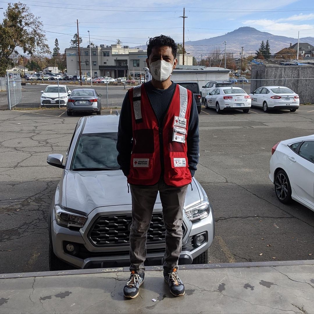 Red Cross volunteer wearing a mask standing in front of a truck