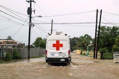 Red Cross vehicle driving through flooded streets