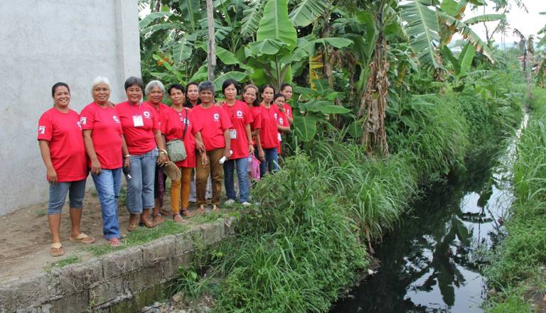 Philippine Red Cross volunteers stand near canal