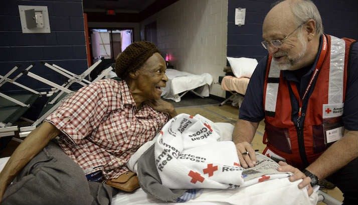 red cross volunteer conversing with elder lady in shelter