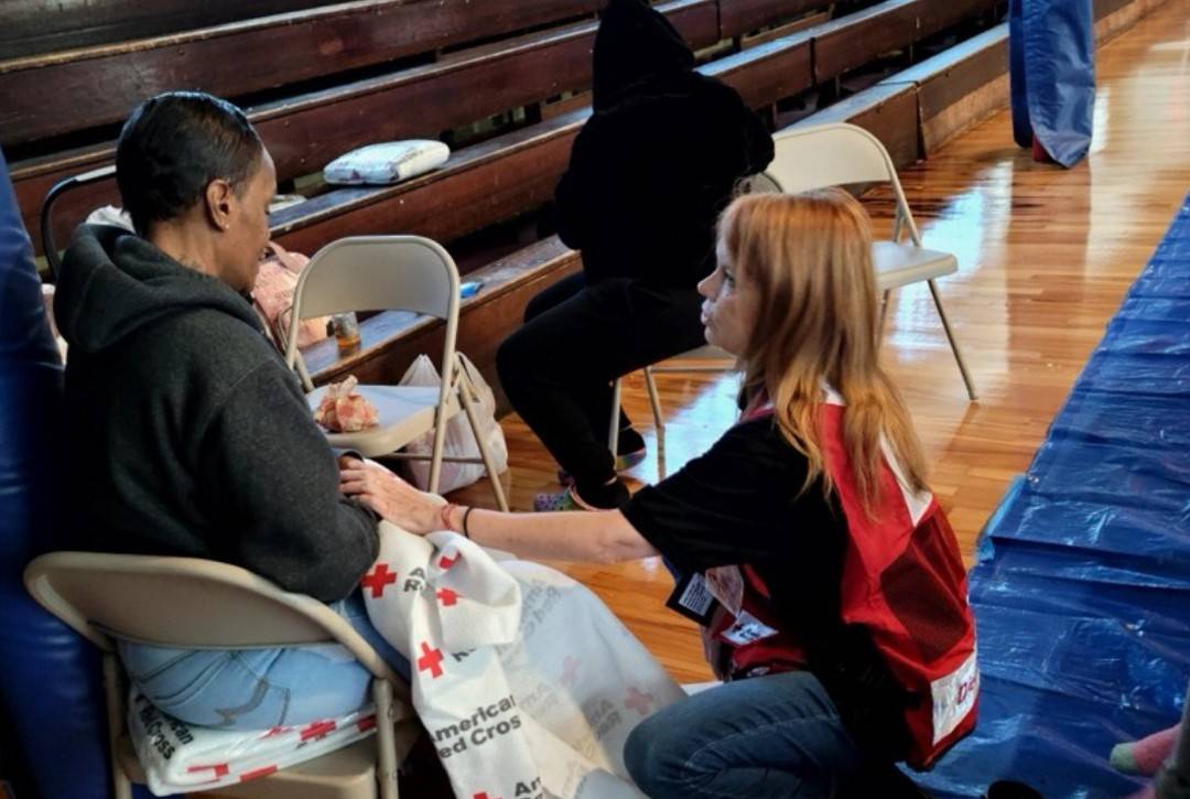 A Red Cross volunteer comforts a woman at a disaster shelter