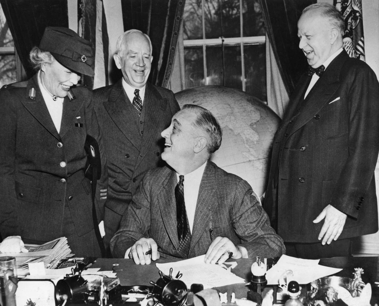 March 1943. The White House, Washington, DC. In his White House study, President Franklin D. Roosevelt signs the proclamation naming March the official Red Cross Month.  Left to right: Mrs. Dwight F. Davis, National Director of the Red Cross Volunteer Social Services; Norman Davis, American Red Cross Chairman; President Roosevelt; Walter Gifford, of the War Fund Campaign.  The goal of the 1943 War Fund Drive is $135,000,000.  The Red Cross Courier, April, 1943, p. 30.  Photo purchased from ACME for general use.
