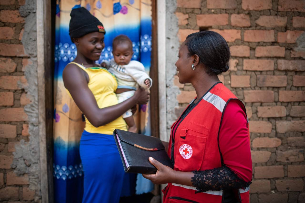 red cross worker speaks to lady with baby