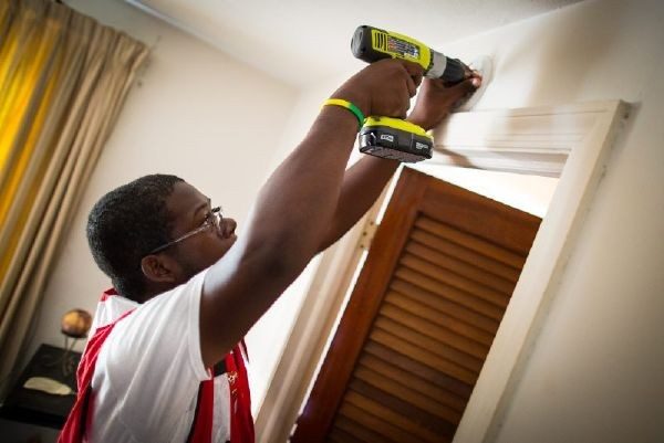 Red Cross volunteer installing smoke alarm in house.