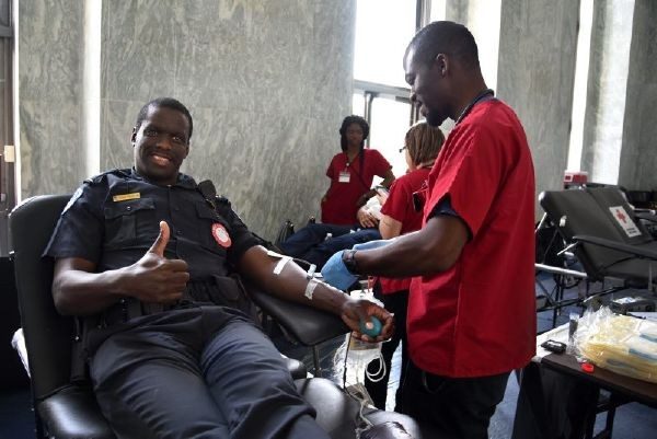 red cross volunteer aiding officer donating blood