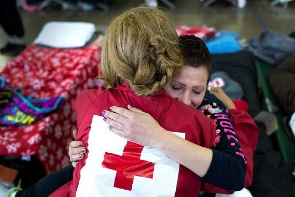 Red Cross volunteer hugging woman to comfort her