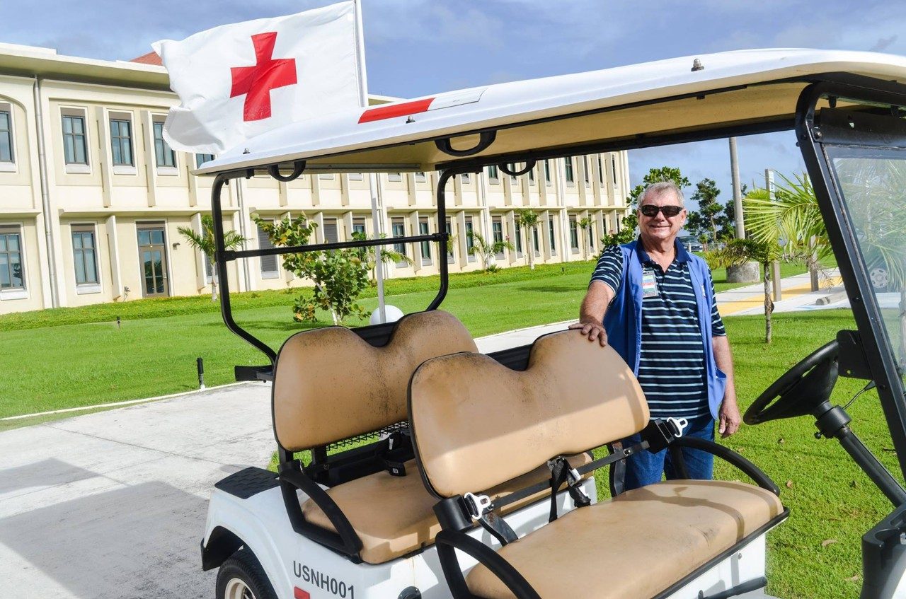 Man standing next to Red Cross golf cart