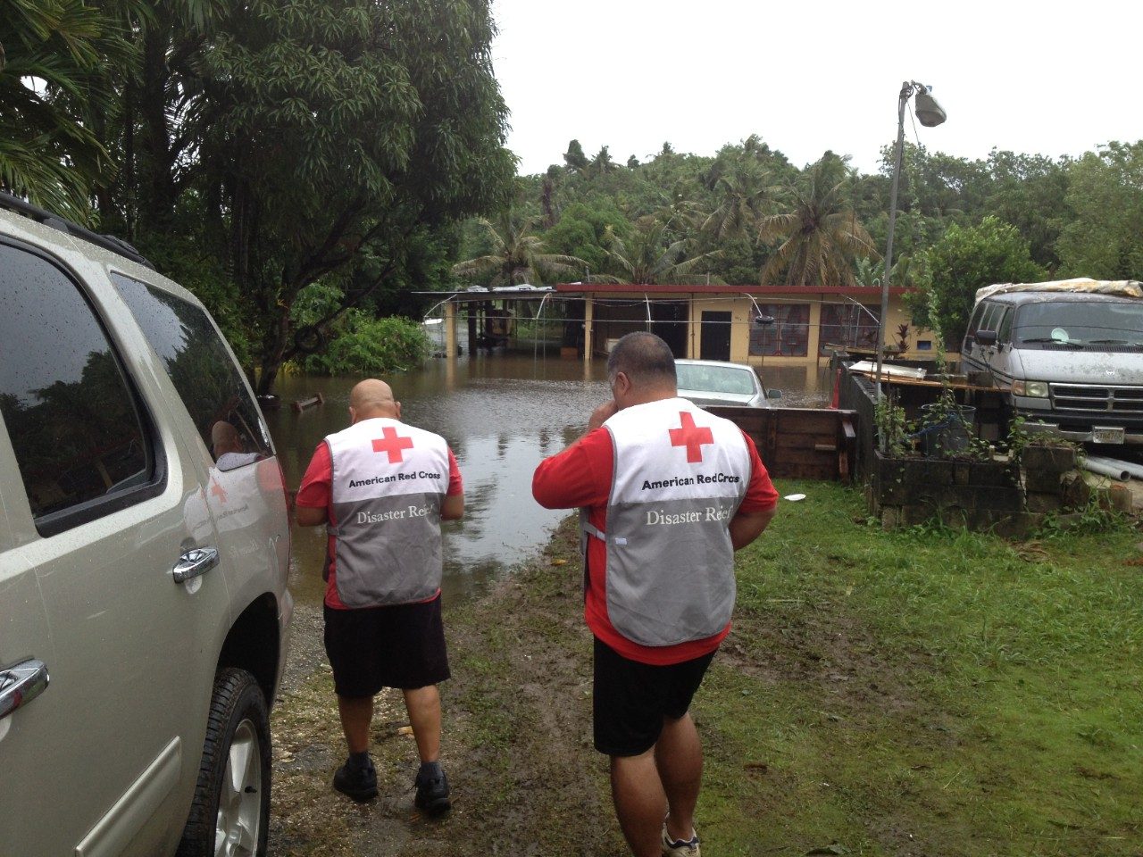 Two Red Cross volunteers in front of flooded home