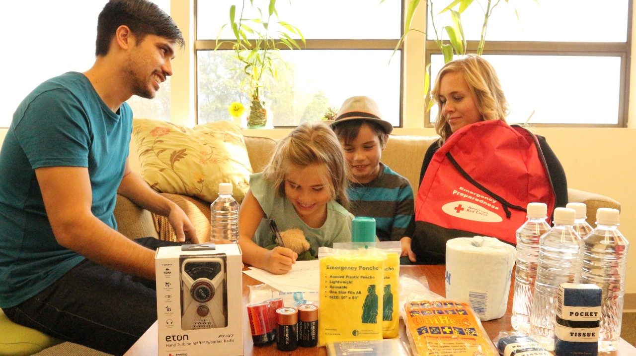 Family with disaster kit spread out on table