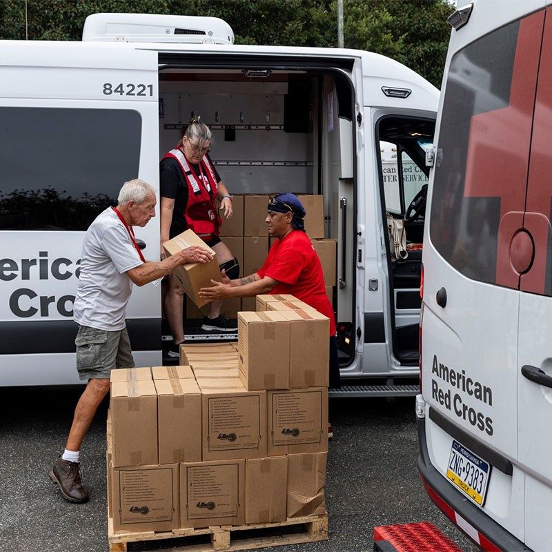 Red Cross volunteers unloading boxes from a Red Cross vehicle