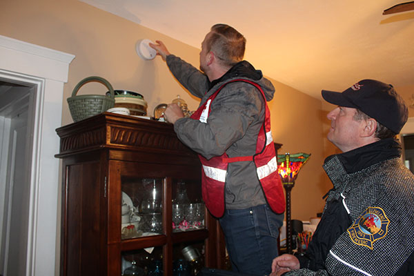 Red Cross volunteer installing smoke alarm on wall