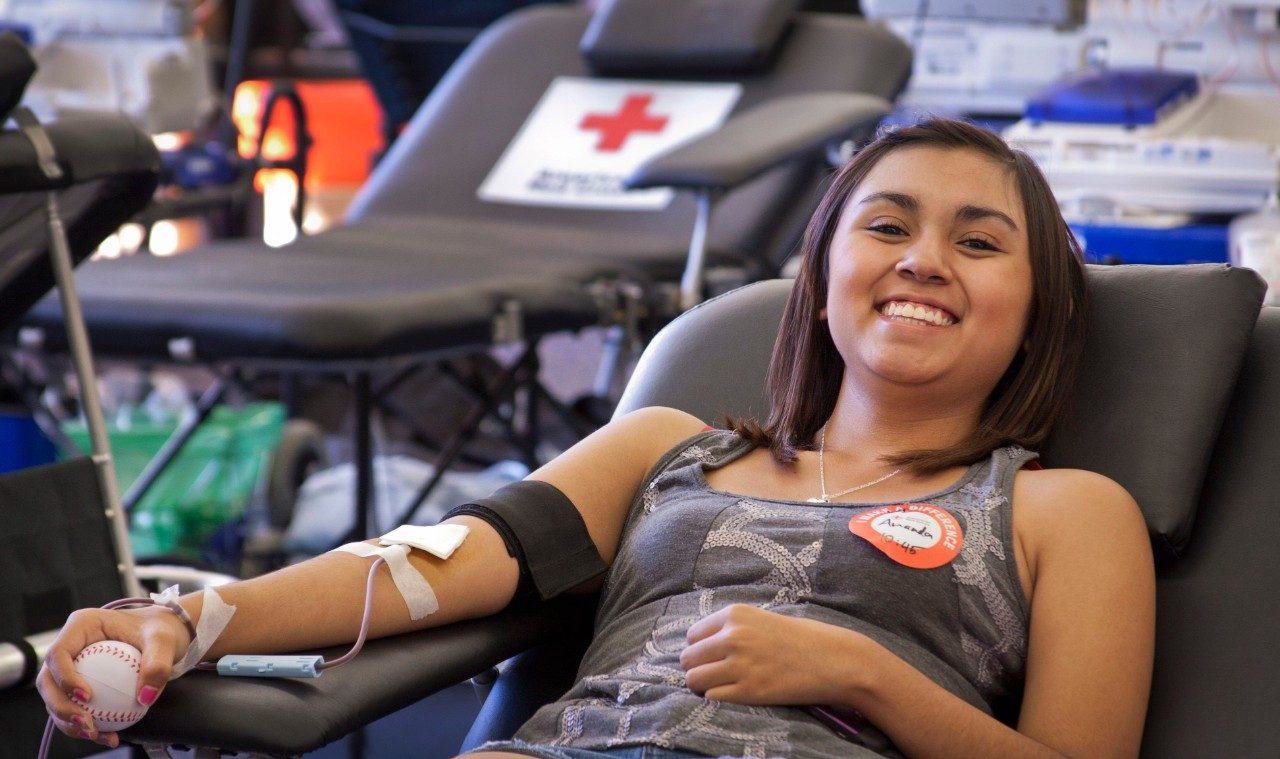 Young woman sitting in a chair and giving blood at a blood drive