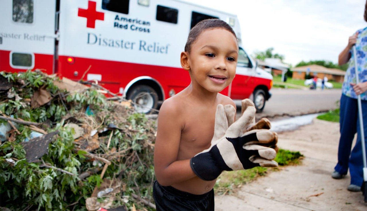 A young boy clearing debris from a front yard