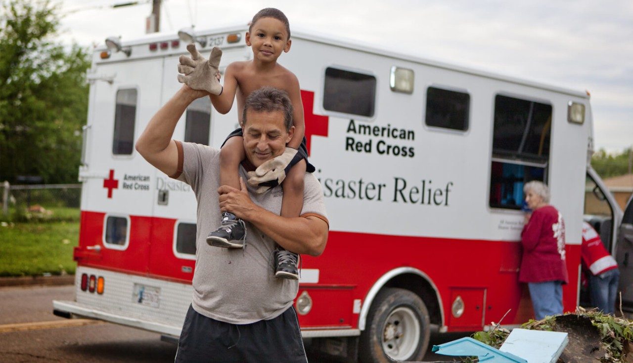 4-year-old Devion Hambrick wears a pair of his father’s work gloves as he clears debris.