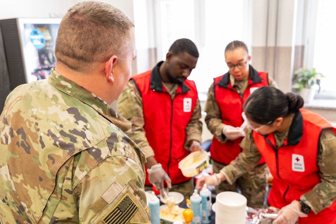 Red Cross volunteer speaking with young woman in military uniform