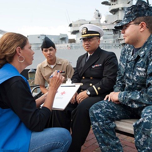 red cross volunteer talks with service members