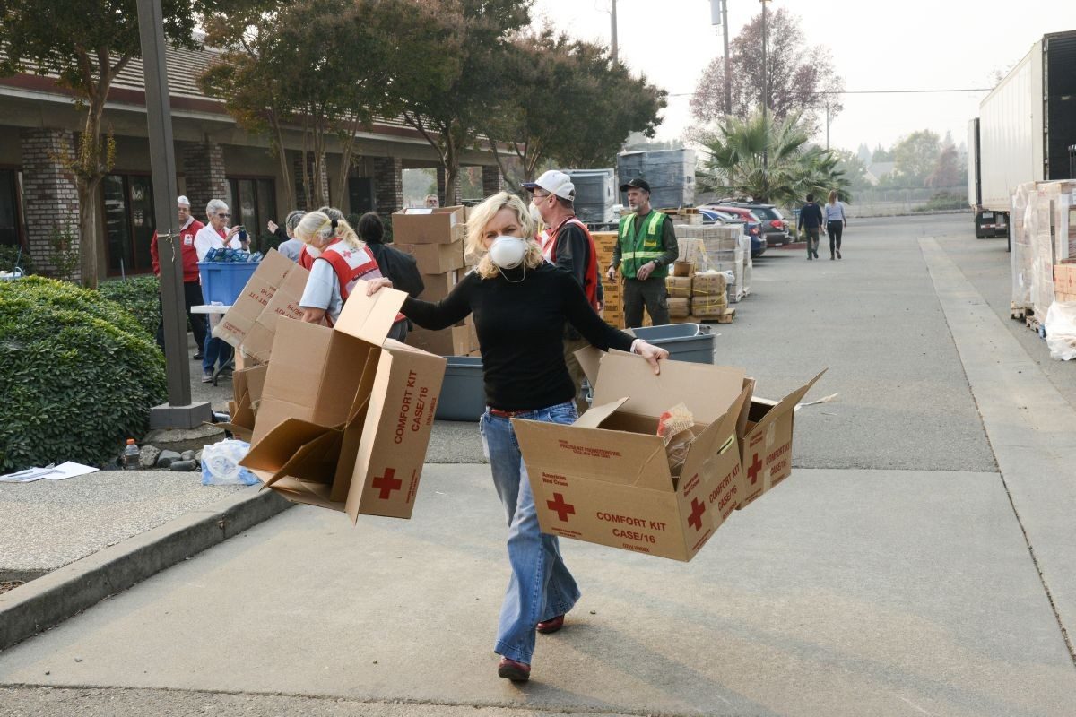 red cross volunteer carrying empty cardboard boxes for making survival kits