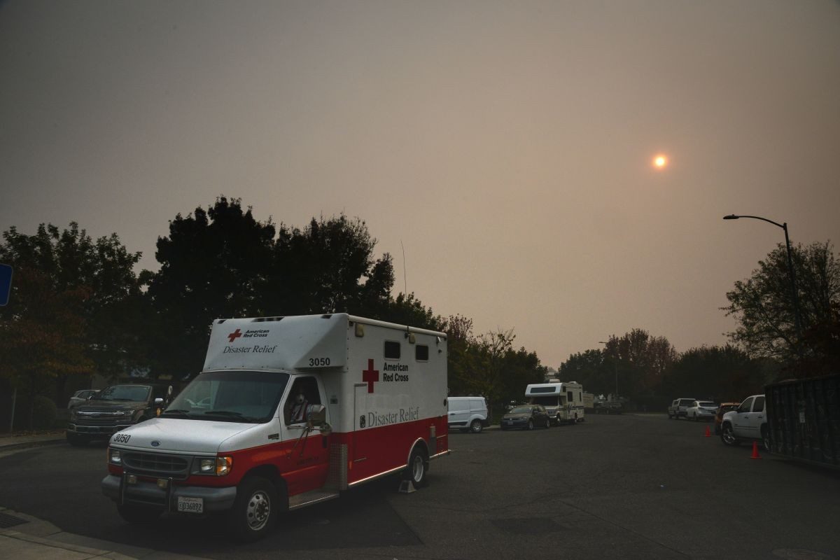 red cross emergency response vehicle driving under a smoke filled sky