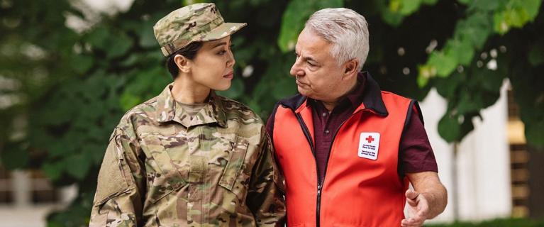 military memeber in uniform talking with red cross volunteer