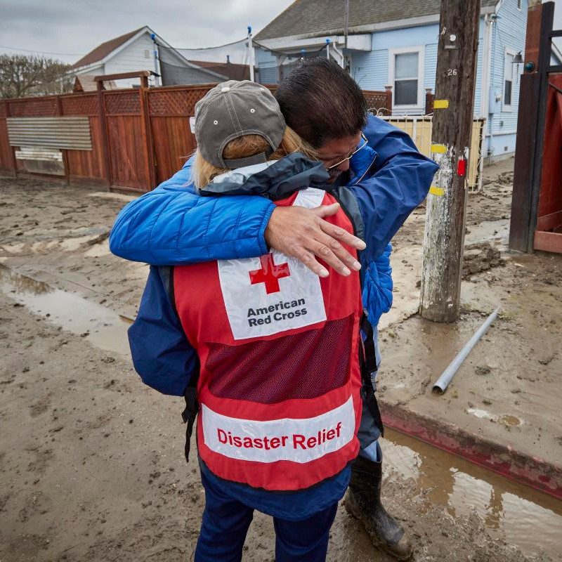 voluntario abrazando a un hombre en una calle inundada